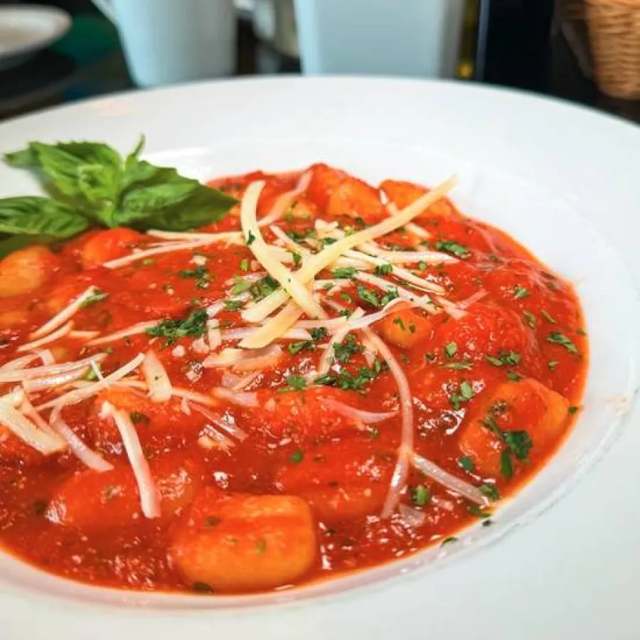 gnocchi della casa served in a white plate with some garnishing on the top