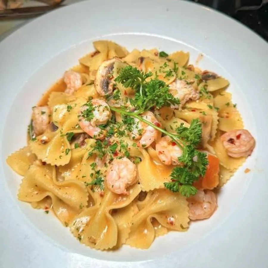 white bow pasta served with some shrimps in a white plate